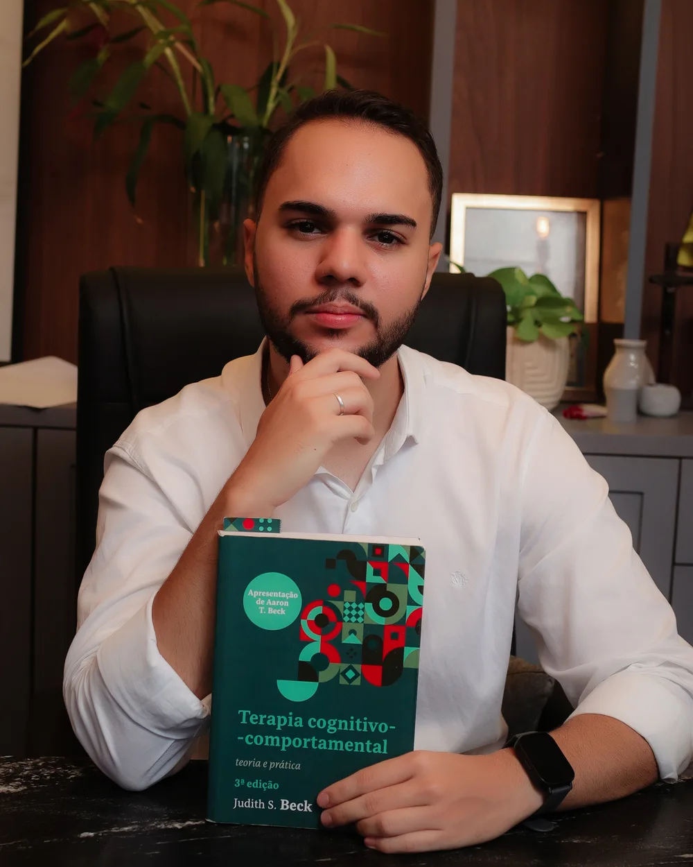 Fábio de Freitas com um livro de Terapia Cognitivo-Comportamental.